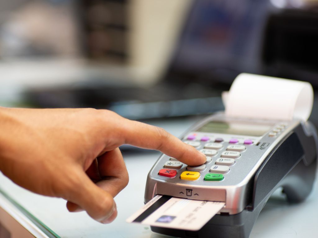 Una mano paga con tarjeta para probar cómo emitir boletas electrónicas e imprimir el comprobante