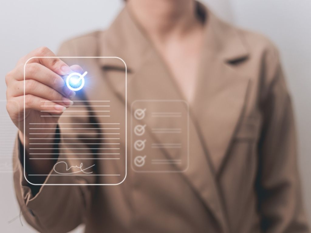 Una empresaria simula firmar en el aire con un lápiz, el dibujo de un documento, representando que pudo comprar un certificado digital para factura electrónica.