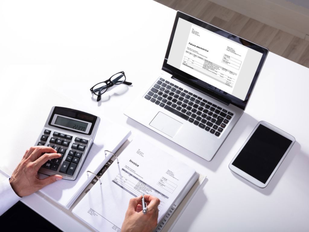 Una persona sentada frente a un computador revisa una factura electrónica.