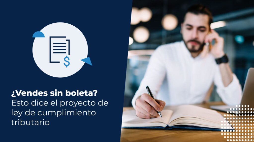 Hombre barbudo con camisa blanca escribiendo en un cuaderno con un lápiz, mientras habla por teléfono y tiene una computadora al lado, en un entorno de oficina o cafetería. Está buscando información sobre el proyecto de ley de cumplimiento tributario.